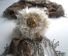 two scarves with flowers and beads on them sitting on a white counter top next to each other