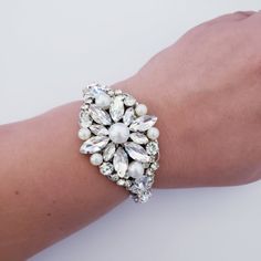 Beautiful Bridal Bracelet . Made with Crystals and pearls set in rhodium plated metal. This bracelet is about 1 1/4 inches wide . It is an open bangle so it will fit any size. Pearls are available in white and ivory. the pictures are taken with ivory pearls. Matching earrings are available at this link: https://www.etsy.com/listing/721180019/vintage-pearl-rhinestone-drop-earrings?ref=shop_home_active_1 Matching hair comb: https://www.etsy.com/listing/703183928/vintage-oval-shape-crystal-rhinesto Silver Beaded Bracelets For Wedding, Silver Beaded Bangle Bracelets For Wedding, Silver Jeweled Bracelets For Weddings, Silver Beaded Bangle For Party, Silver Pearl Bracelet For Party, Silver Beaded Pearl Bracelet For Party, Silver Bangle Pearl Bracelet For Weddings, Silver Pearl Bangle For Wedding, Silver Crystal Pearl Bracelet With Beads