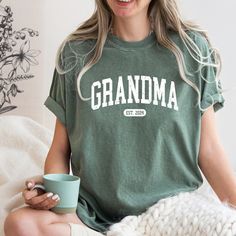 Comfort Colors® Grandma Est. 2024 Shirt, Grandma T-Shirt, Nana Shirt, Gift For Grandma, Gift For Mom, Retro  Grandma Shirt, Gift For Nana A Comfort Colors shirt is a type of casual t-shirt that is known for its softness, relaxed fit, and muted color palette. Typically made from 100% cotton, these shirts have a vintage feel and are often favored for their comfortable, worn-in look. This classic unisex jersey short sleeve and long sleeve tees fits like a well-loved favorite. Soft cotton and quality print make users fall in love with it over and over again. These t-shirts have-ribbed knit collars to bolster shaping. The shoulders have taping for better fit over time. Dual side seams hold the garment's shape for longer.  *6.1 oz./yd² (US), 10 oz/L yd (CA), 100% ring spun cotton, 30 singles *Ga Green Short Sleeve Tops With Name Print, Green Short Sleeve Top With Name Print, Green Relaxed Fit Top With Name Print, Green Casual Shirt With Name Print, Green Relaxed Fit T-shirt With Name Print, Casual Green Shirt With Name Print, Green Cotton Shirt With Name Print, Green Crew Neck Shirt With Name Print, Nana Shirts