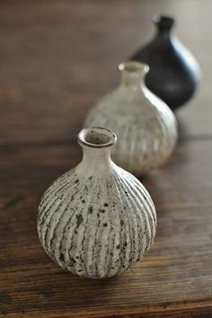 three small vases sitting on top of a wooden table