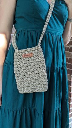 a woman wearing a green dress holding a crocheted purse