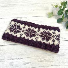 a close up of a knitted object on a wooden surface with flowers in the background