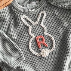 a close up of a knitted sweater with an ornament on the front