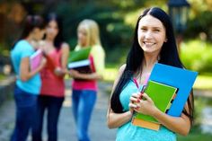 a group of young women standing next to each other holding notebooks and folders