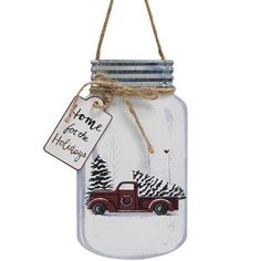 a glass jar with a red truck on it and a tag that says home is for the holidays