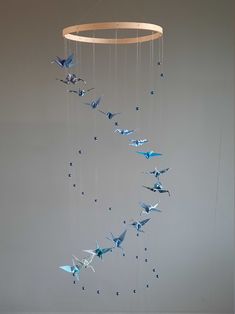 a group of blue origami birds hanging from a circular wooden frame on a gray wall