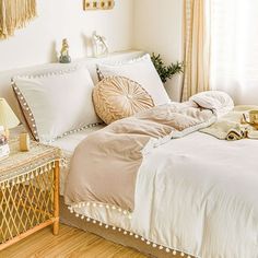 a bed with white sheets and pillows in a bedroom next to a wooden table filled with decorative items