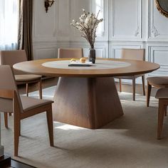 a dining table with chairs around it and a vase on the table next to it