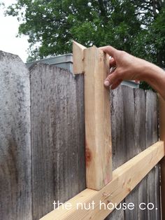 a hand is holding the top half of a wooden fence