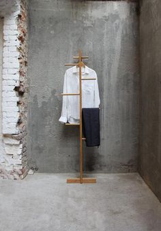 a white shirt is hanging on a clothes rack in a room with exposed brick walls