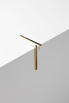 an object that is on top of a white wall and has a long bar attached to it