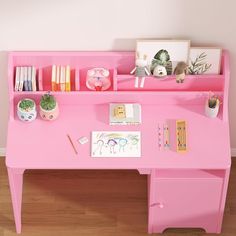 a pink desk with books, pencils and pictures on it