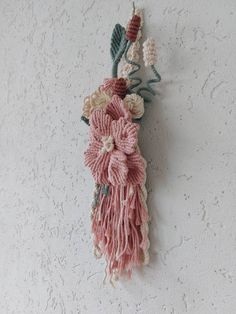 a wall hanging with flowers and leaves on it's side, attached to the wall