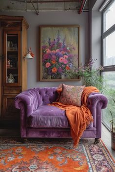 a purple couch sitting in front of a window next to a painting on the wall