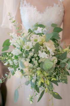 a bridal holding a bouquet of white flowers and greenery