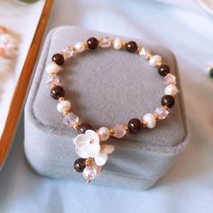 a bracelet with flowers on it sitting on top of a white cloth covered tablecloth