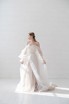 a woman in a white dress is standing on the floor with her hands behind her back