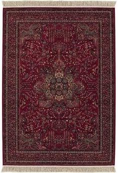 a red rug with an intricate design on the center and fringes in the middle