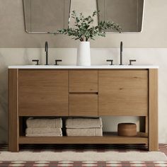 a bathroom vanity with two mirrors above it and towels on the bottom shelf next to it