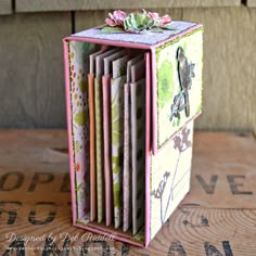 a close up of a small box on a wooden table with flowers and birds in it