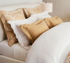 a bed with white and gold pillows on it