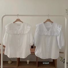 two white blouses hanging on clothes racks