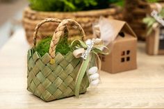 a small basket filled with green grass and white eggs on top of a wooden table