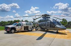 a helicopter is parked on the tarmac next to a truck