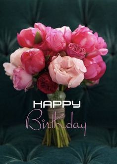 a vase filled with pink and red flowers on top of a green table next to a black background