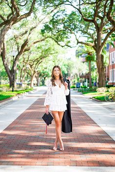 a woman is walking down the street in her graduation gown and holding a black bag