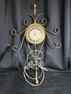 an ornate clock is on display against a black background with swirly arms and feet