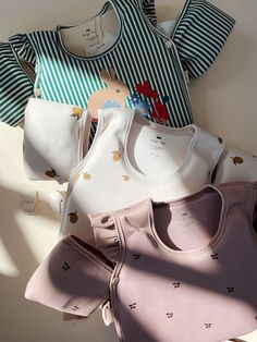 several baby bibs and ones laying on top of each other in front of a white wall