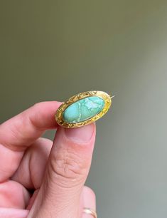 * Antique 1900's Art Nouveau era, American handmade brooch, made of solid 14 carat gold, framing a natural unstabilized light greenish blue turquoise cabochon. Adorned by traditional scroll etch detailing along the border of the brooch.  * No stampings or hallmarks, common for antique pieces of this age.  * Measurements- 1.05 inches long x 0.57 inch wide  * Weight- 2.8 grams Antique Green Gemstone Brooches, Vintage Yellow Gold Turquoise Cabochon Ring, Antique Yellow Gold Turquoise Cabochon Ring, Antique Yellow Gold Turquoise Ring Gift, Antique Turquoise Ring In Yellow Gold For Gift, Turquoise Cabochon Brooch As A Gift, Turquoise Cabochon Brooch For Gift, Antique Green Turquoise Ring As Gift, Mc Gregor