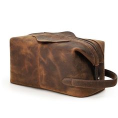 a brown leather toiletry bag with zippers on the front and side, sitting against a white background