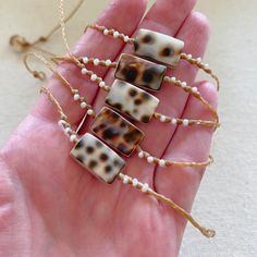 These beautiful tiger cowrie pieces are fused with mother of pearl so both sides are gorgeous. They are accented with freshwater seed pearls and woven onto braided waxed cord. Waxed cord is strong and waterproof🌊 Perfect for women with an active lifestyle.🧜🏻‍♀️ The cowrie pieces measure 5/8" by 3/8". Finished with a mother of pearl button clasp. Cowrie shells are from nature so each piece will be slightly different and unique.﻿💙Handmade by me with love in coastal Southern Maryland.💙Carefull Adjustable Cowrie Shell Beachy Jewelry, Handmade Cowrie Shell Decor, Bohemian Shell Braided Bracelets For Beach, Bohemian Shell Braided Bracelets For Vacation, Adjustable Shell Cord Jewelry, Adjustable Cowrie Shell Jewelry For Beach Season, Adjustable Natural Cowrie Shell Necklace, Artisan Adjustable Cowrie Shell Jewelry, Adjustable Bohemian Beaded Bracelets With Cowrie Shell