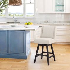 a kitchen with white cabinets, blue island and stools next to the countertop