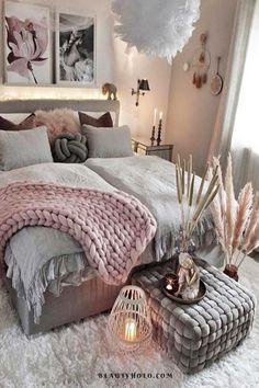 a bedroom with a large bed covered in pink blankets and pillows, surrounded by candles