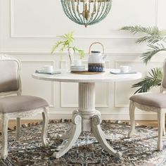 a dining room table with two chairs and a chandelier