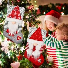 two young children decorating christmas stockings on a tree with santa's stocking