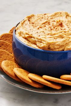 a blue bowl filled with dip surrounded by crackers