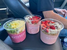 three cups filled with food sitting on top of a seat in front of a man