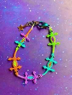 a colorful bracelet with beads and stars on purple surface next to blue stardust background