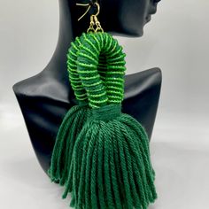 a pair of green tasseled earrings sitting on top of a mannequin head