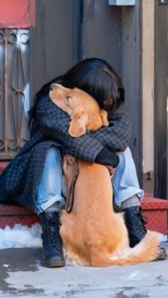 a person sitting on the ground hugging a dog