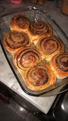 several cinnamon rolls in a glass dish on a counter