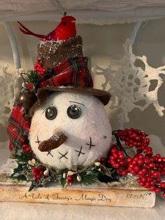 a snowman with a hat and scarf on top of a wooden box filled with berries