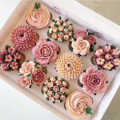 cupcakes decorated with pink and yellow flowers in a box