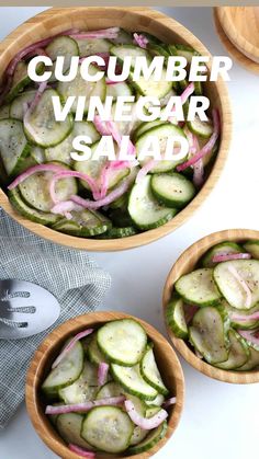 three wooden bowls filled with cucumbers and onions on top of a white table