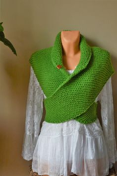 a green knitted shawl draped over a white dress