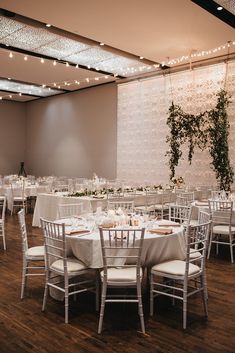 a room filled with tables and chairs covered in white linens